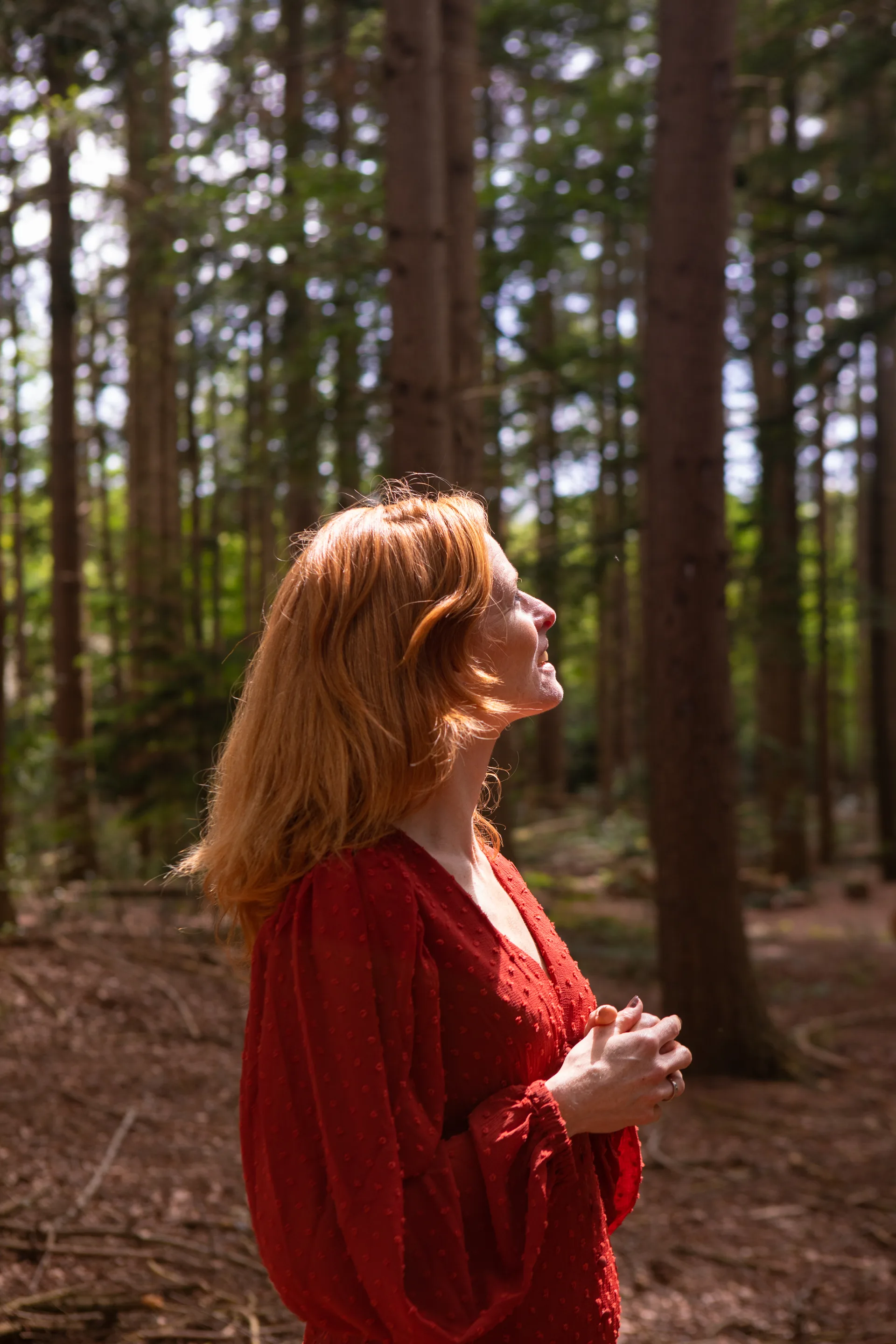 Chantal in het bos, kijkend naar het licht tussen de bomen